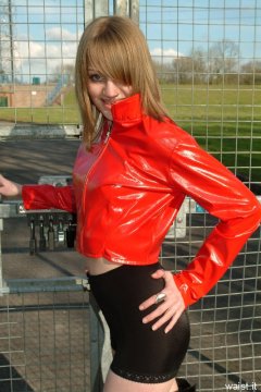 Carlie models red PVC jacket and black shiny pantie girdle worn as hot pants