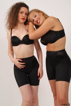 Chiara and Nikki in black multiway bras and shiny lycra long-leg pantie girdles worn as cycling shorts