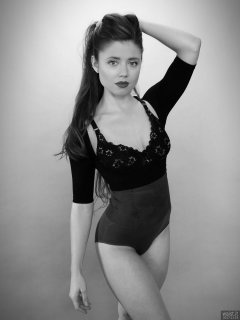 Charlene Joy in black bra and posture top, and purple high-waist control briefs worn as hotpants