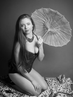 Charlene Joy in tightly-laced blue underbust corset, worn over black bra and high-waist control briefs