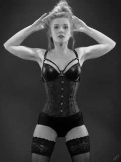 Rebecca Love - tightly-laced black underbust corset, with black wetlook bra and shinly black high-waist girdle worn as hotpants