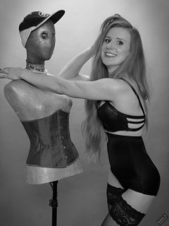 Rebecca Love - tightly-laced black underbust corset, with black wetlook bra and shinly black high-waist girdle worn as hotpants