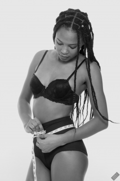 Caleann measuring herself in vintage black sixties-style bra and girdle