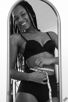 Caleann measuring herself in vintage black sixties-style bra and girdle