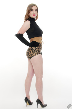 Harriet in black stretchy top, tight leather corset belt and retro-style animal-print control-briefs worn as hotpants