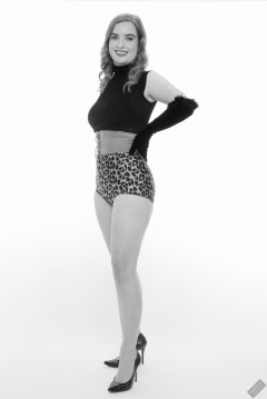 Harriet in black stretchy top, tight leather corset belt and retro-style animal-print control-briefs worn as hotpants