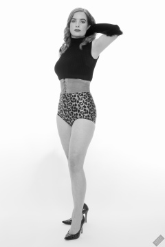 Harriet in black stretchy top, tight leather corset belt and retro-style animal-print control-briefs worn as hotpants
