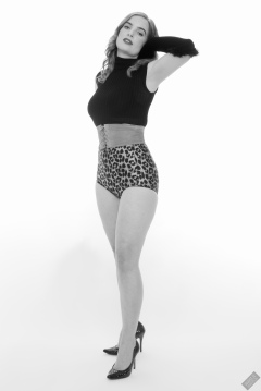Harriet in black stretchy top, tight leather corset belt and retro-style animal-print control-briefs worn as hotpants