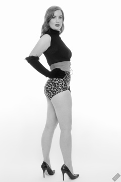 Harriet in black stretchy top, tight leather corset belt and retro-style animal-print control-briefs worn as hotpants