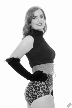 Harriet in black stretchy top, tight leather corset belt and retro-style animal-print control-briefs worn as hotpants