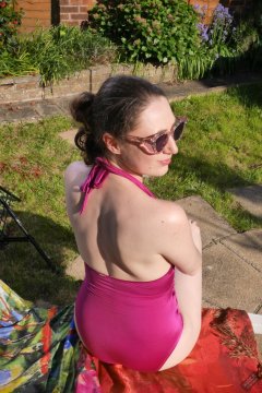 Estella Rose in purple swimsuit exercising in the garden