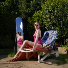 Estella Rose in purple swimsuit exercising in the garden