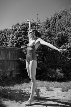 Estella Rose in purple swimsuit exercising in the garden