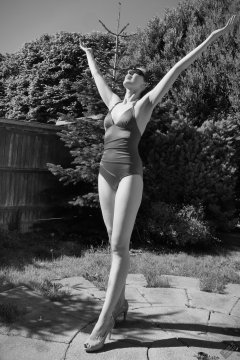 Estella Rose in purple swimsuit exercising in the garden