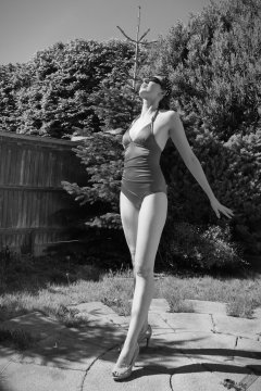 Estella Rose in purple swimsuit exercising in the garden