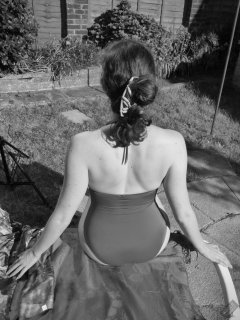 Estella Rose in purple swimsuit exercising in the garden