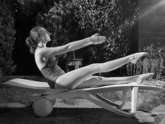Estella Rose in purple swimsuit exercising in the garden