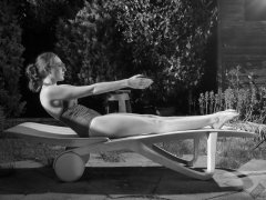 Estella Rose in purple swimsuit exercising in the garden