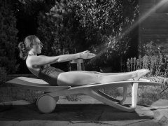 Estella Rose in purple swimsuit exercising in the garden