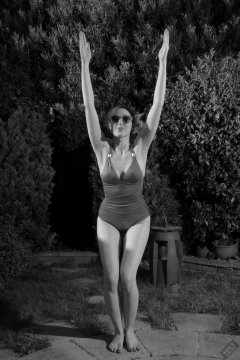 Estella Rose in purple swimsuit exercising in the garden