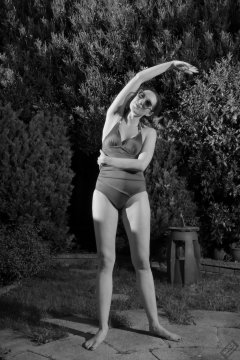Estella Rose in purple swimsuit exercising in the garden