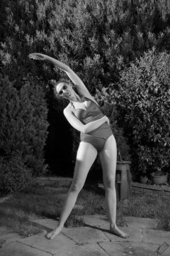 Estella Rose in purple swimsuit exercising in the garden