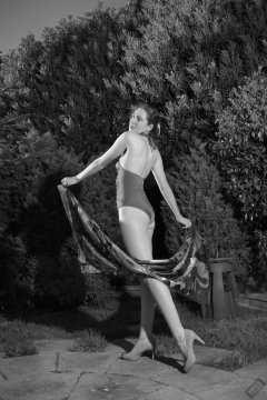 Estella Rose in purple swimsuit exercising in the garden
