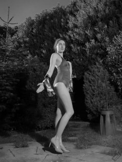 Estella Rose in purple swimsuit exercising in the garden